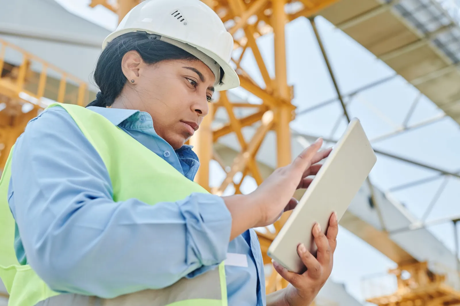 Ingeniera revisando datos de consumo energético en una tablet dentro de una planta industrial